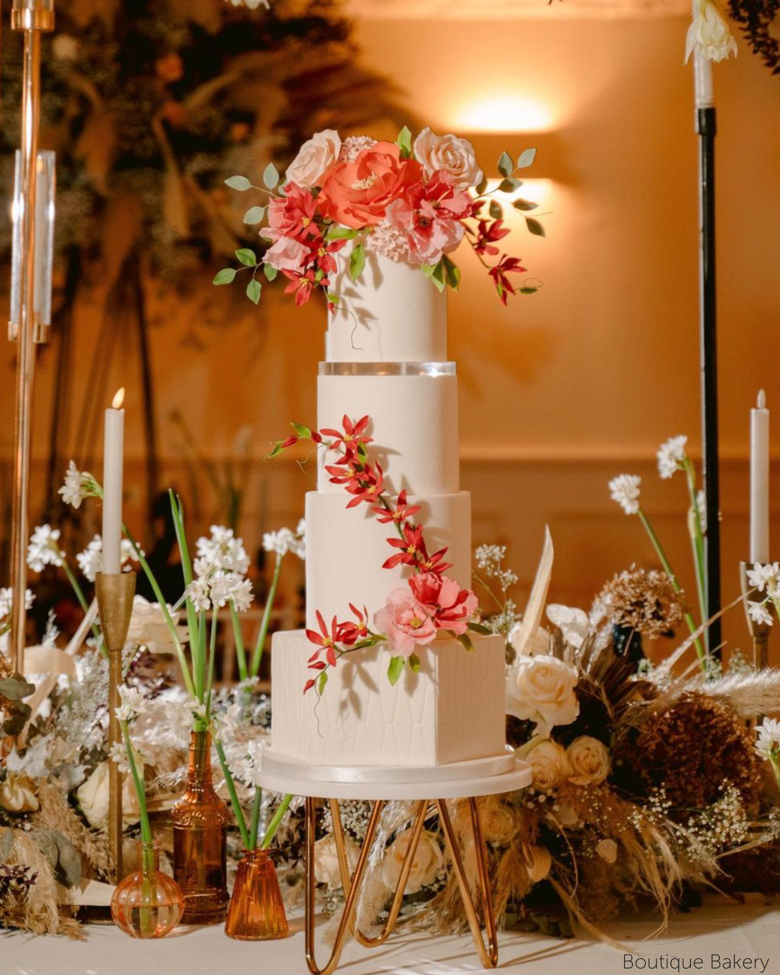 Tall multitiered white cake with red and pink florals, the layers are separated using 15mm Acrylic Cake Separators - Prop Options