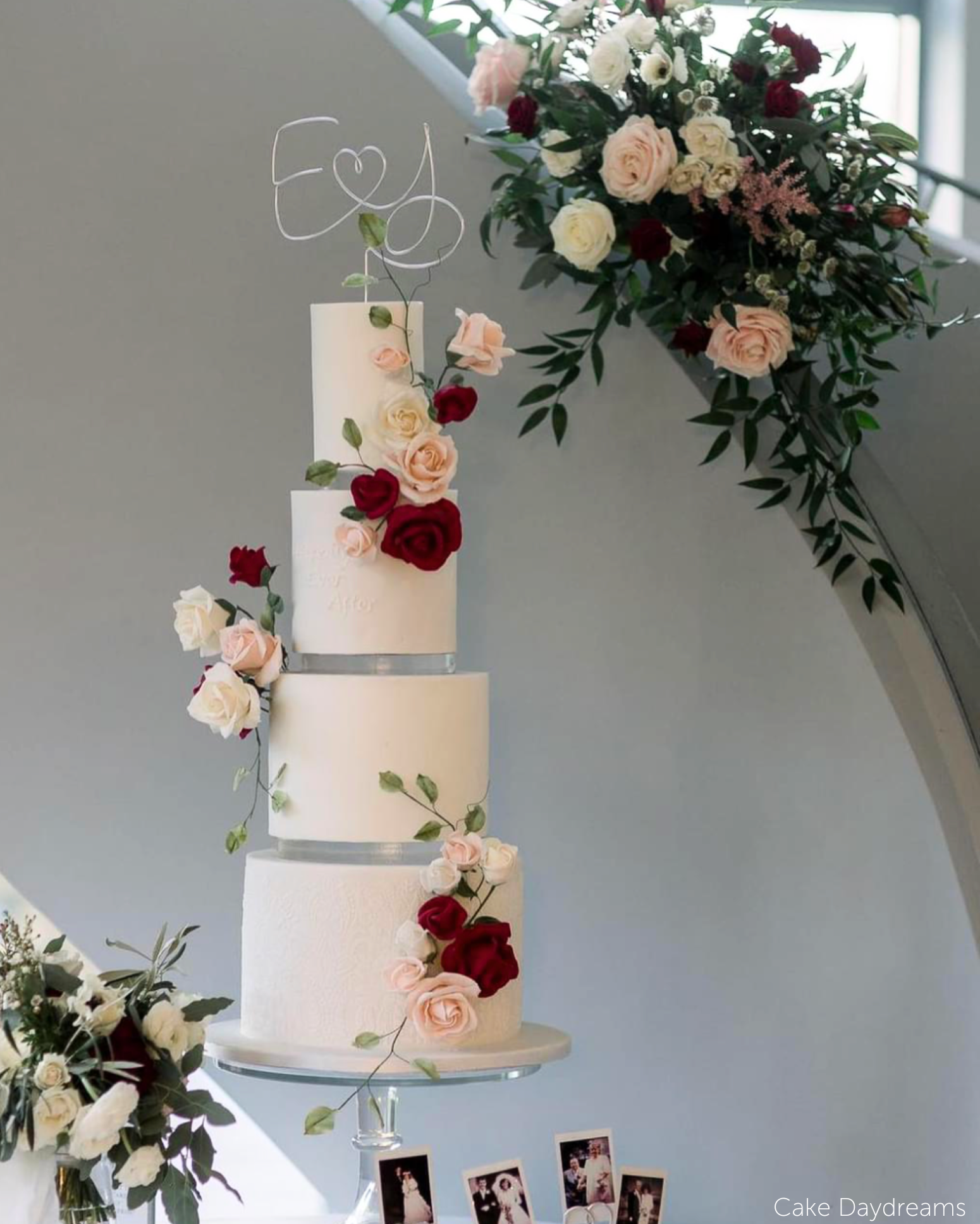 Multilayered white cake with rose decorations and a white topper with the initials E <3 J, each of the layers is separated with a 15mm Acrylic Cake Separator - Prop Options