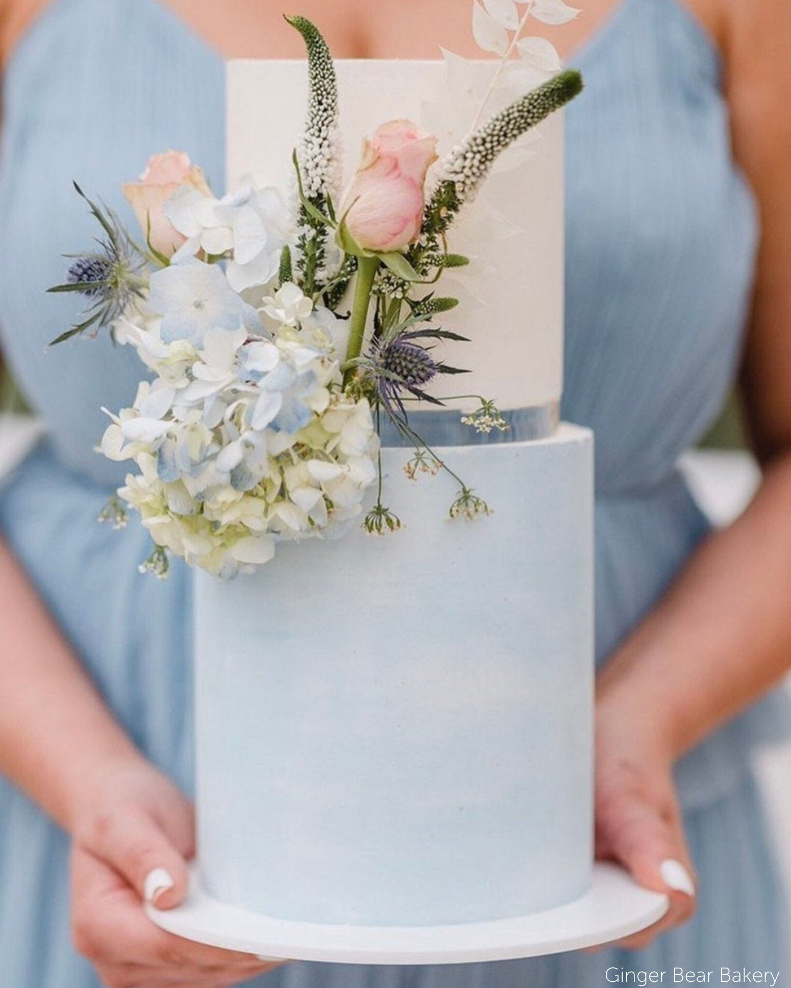 Two tier pastel blue and white cake with pastel coloured flowers, the tiers are separated using a 15mm Acrylic Cake Separator - Prop Options