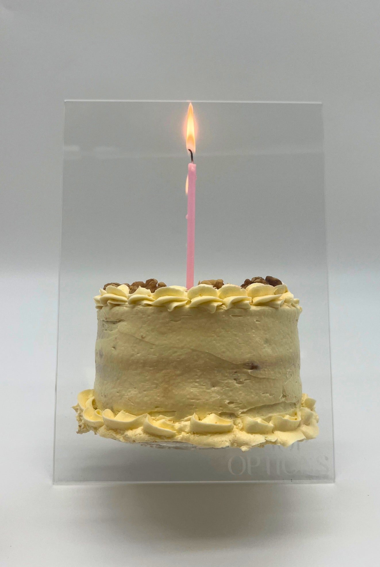 Clear acrylic cake easel stand for displaying decorated cakes, shown holding an 8-inch cake.