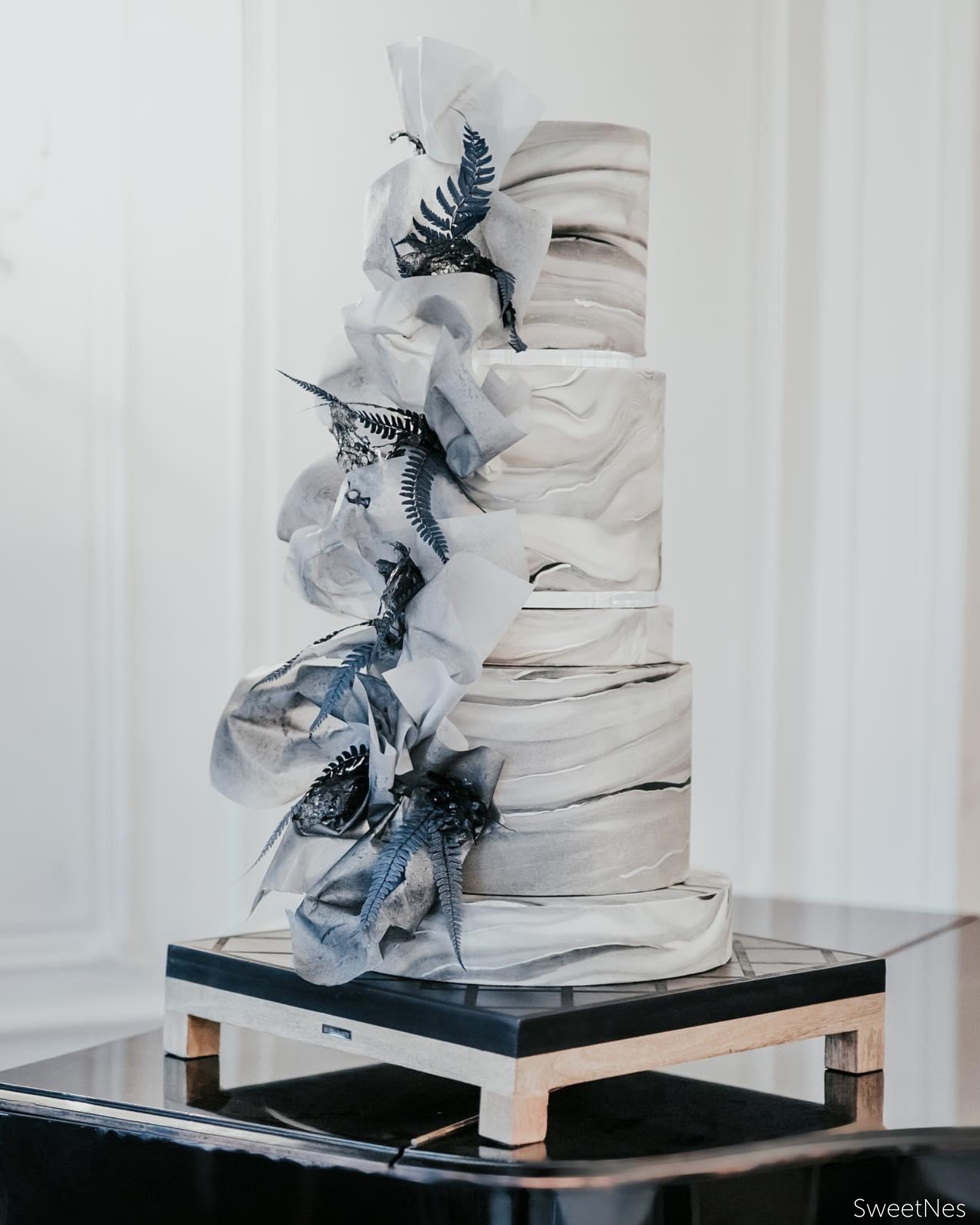 Elegant marbled white and grey cake with grey blue ribbon and leaf decorations down the side, the tiers are separated using 15mm Acrylic Cake Separators - Prop Options