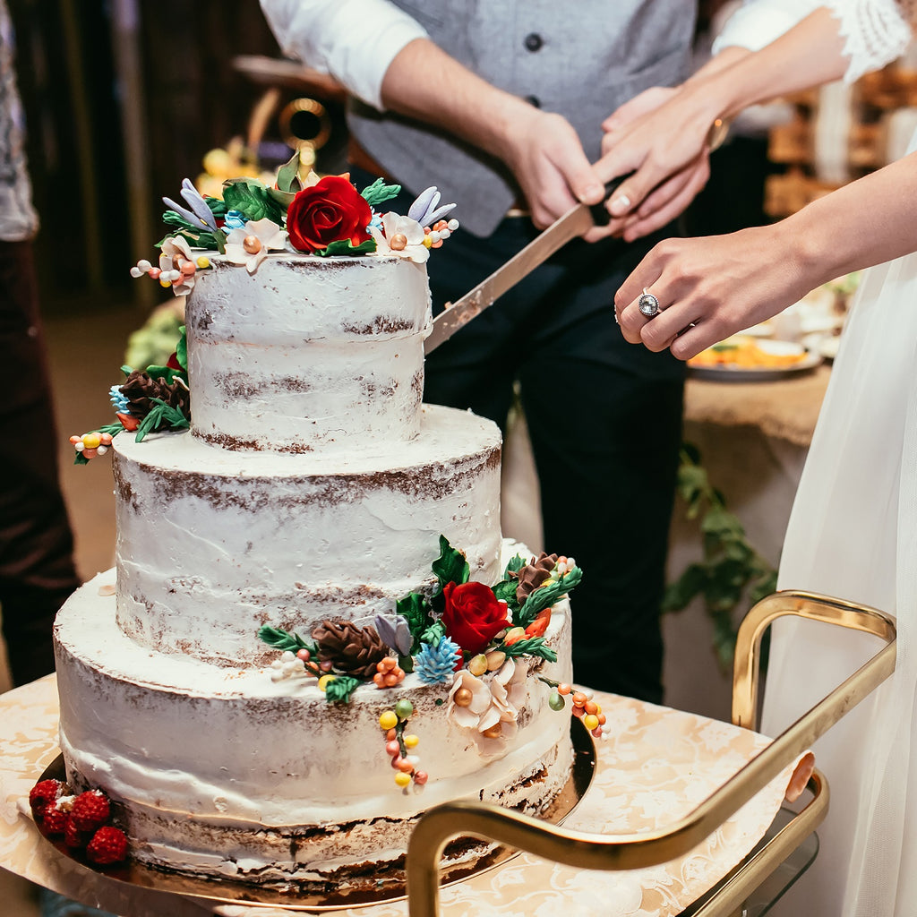 cutting a rustic wedding cake
