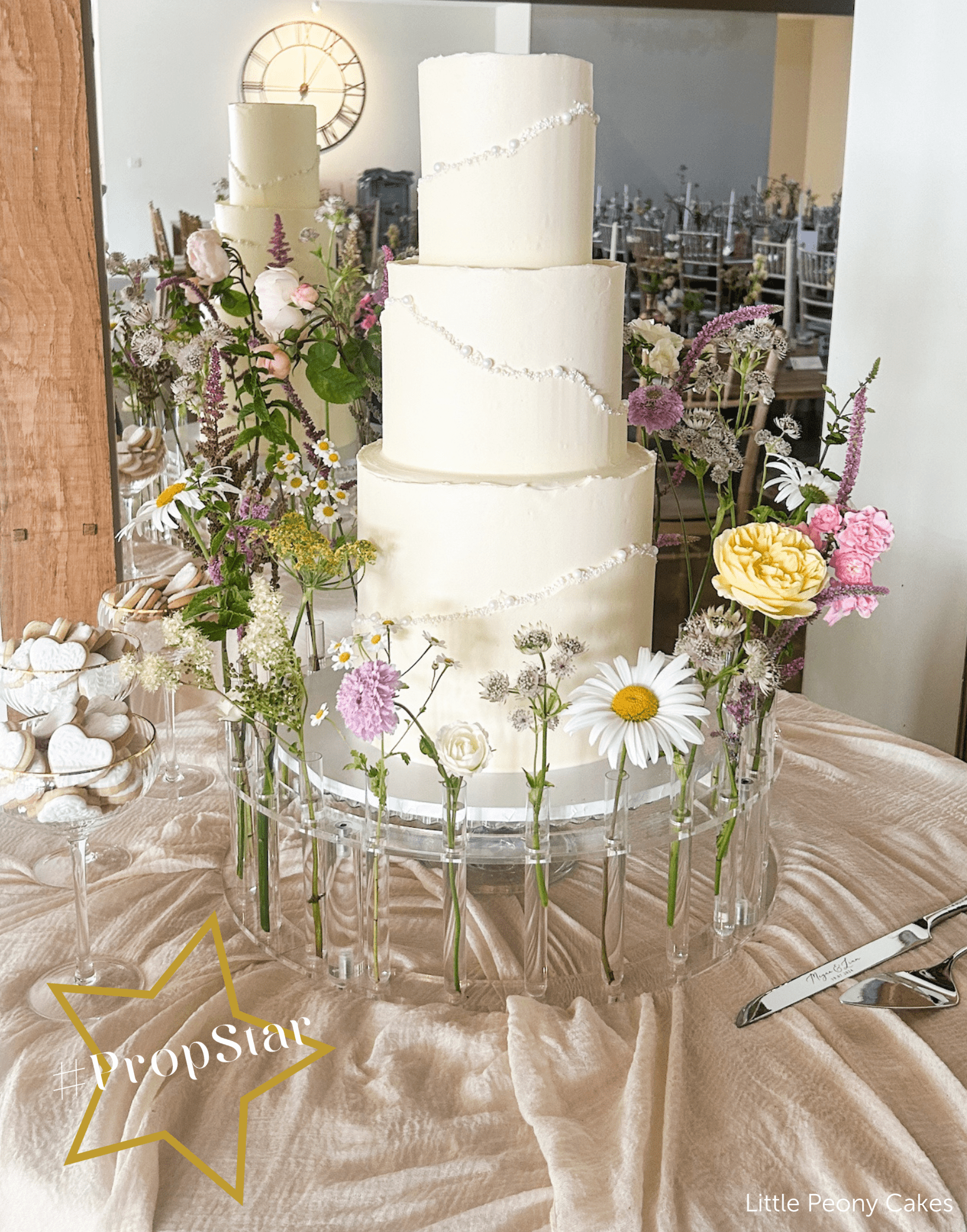 Garden party cake centrepiece styled on The Floral Crown platform stand with foliage for an outdoor marquee reception