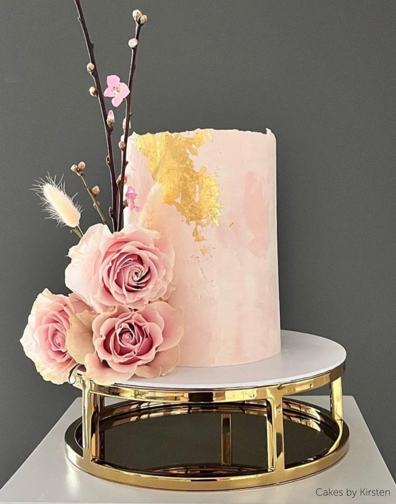 Pink floral cake being held up by Gold 10" Round Metallic Cake Spacer - Prop Options