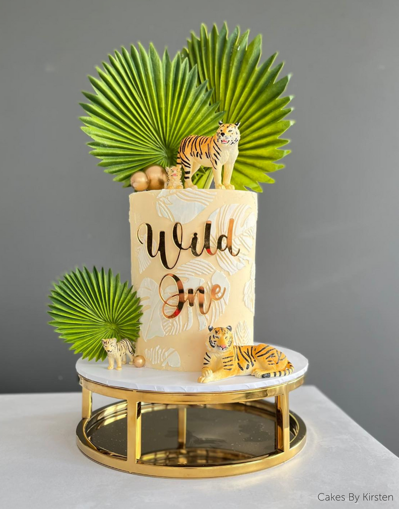 Pastel yellow jungle themed cake with leaf and tiger decorations being held up by a Gold 10" Round Metallic Cake Spacer - Prop Options
