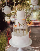Outdoor wedding cake displayed with Prop Options Floral Tiara cake separator in a garden setting