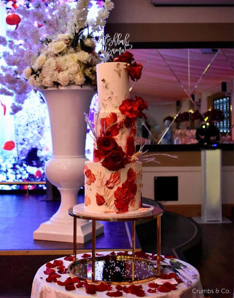 Gold Round Metallic Plinth holding up a cake decorated with red and pink florals with silver writing on the top layer - Prop Options