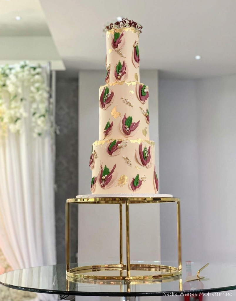 Gold Round Metallic Plinth holding up a multilayered light pink cake with dark pink and green decorations - Prop Options