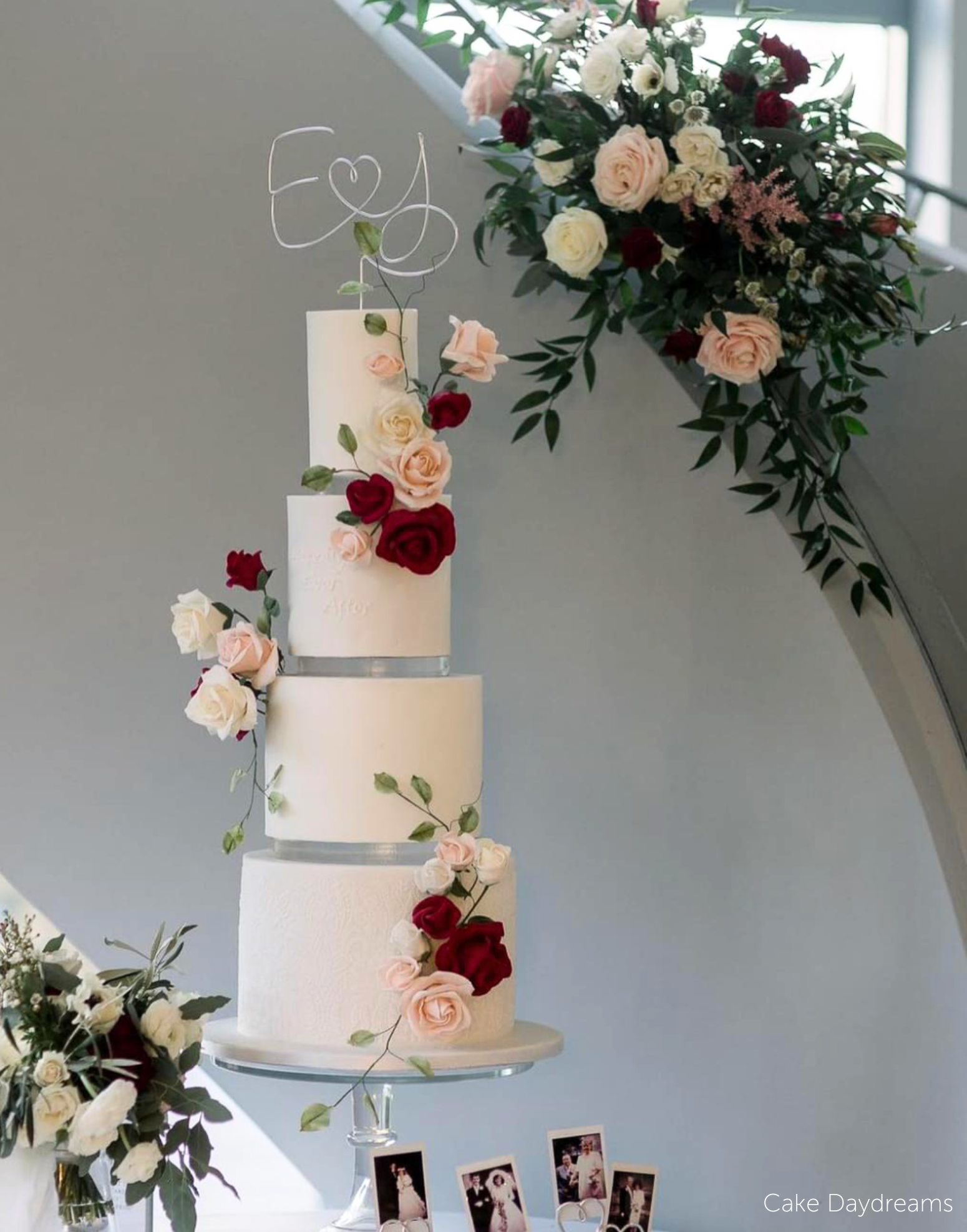 Multilayered white cake with rose decorations and a white topper with the initials E <3 J, each of the layers is separated with a 15mm Acrylic Cake Separator - Prop Options