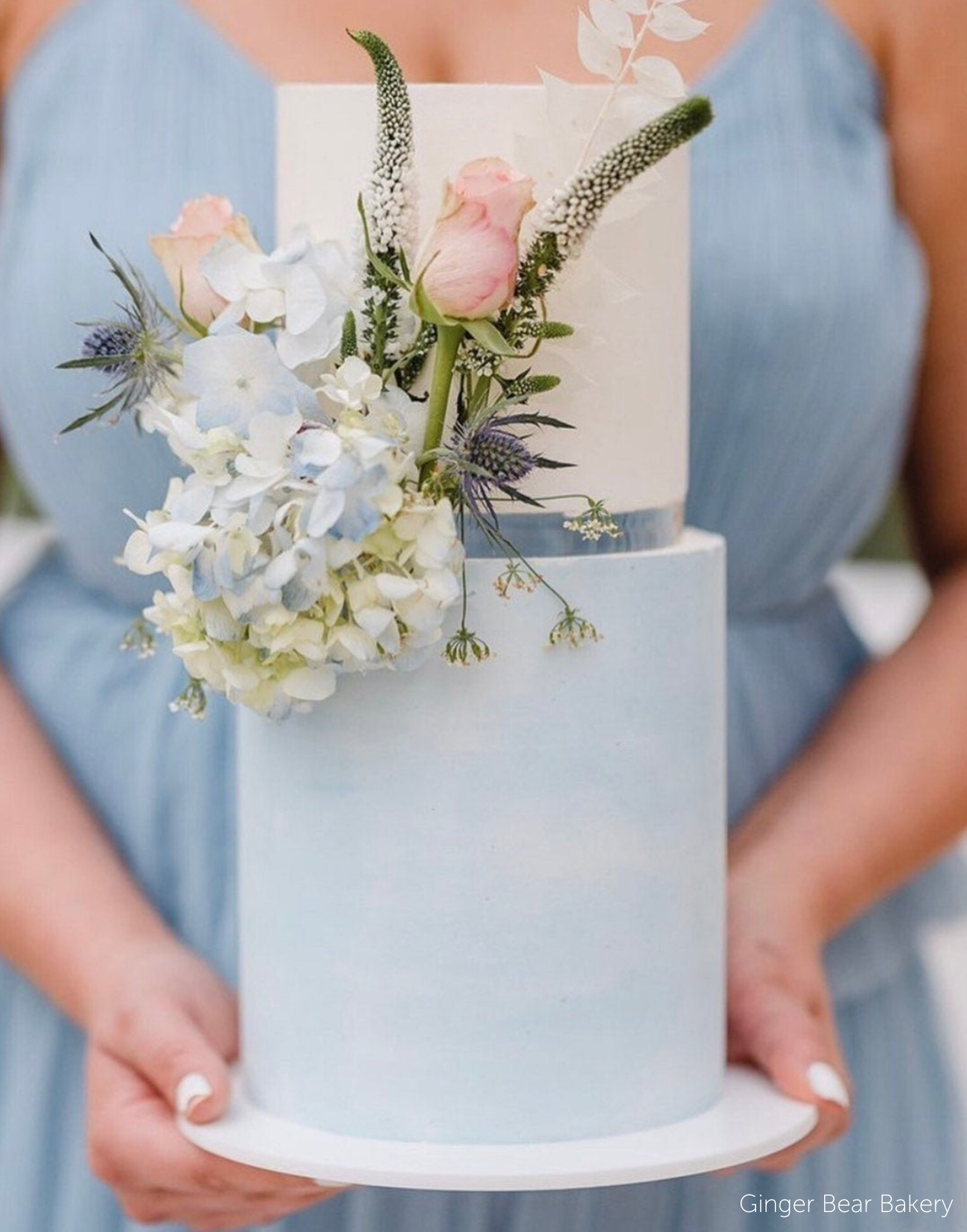 Two tier pastel blue and white cake with pastel coloured flowers, the tiers are separated using a 15mm Acrylic Cake Separator - Prop Options