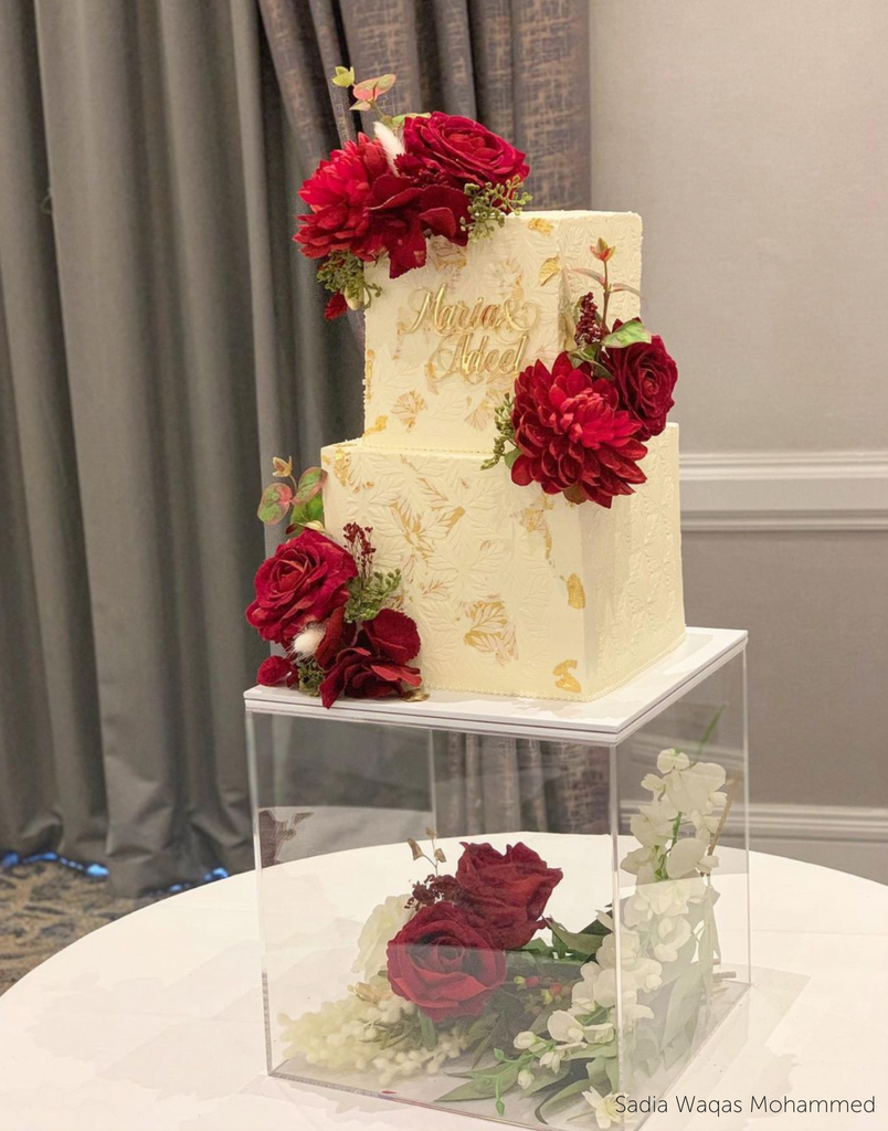 Square Acrylic Fillable Plinth full of white and red flowers holding a square cake decorated with red flowers and gold lettering - Prop Options