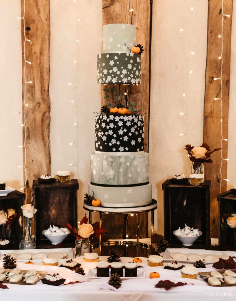 An Autumn themed multilayer cake with black and grey layers, white flower prints and miniature orange pumpkin decorations, the midle of the cake is supported using a PropSecure® Adjustable Central Bar Cake Separator - Prop Options