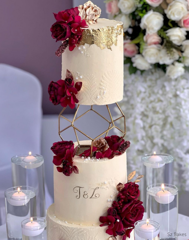 A cream coloured cake with dark red florals and subtle pearl and gold decorations with the top two layers separated by a Geometric Pentagon Spacer - Prop Options