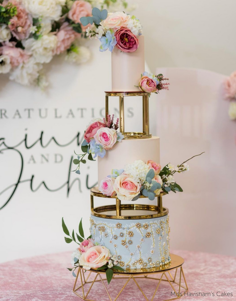 A pastel pink and blue three layer cake with pink and blue flowers, the layers are separated using 6" & 10" Round Metallic Cake Spacers - Prop Options