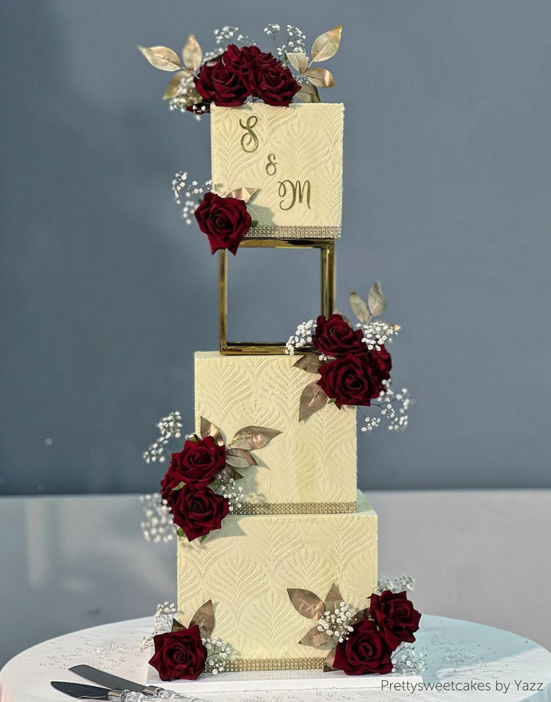 A cream coloured three layer cake with red rose decorations, the top two layers are separated using a Square Metallic Cake Spacer - Prop Options