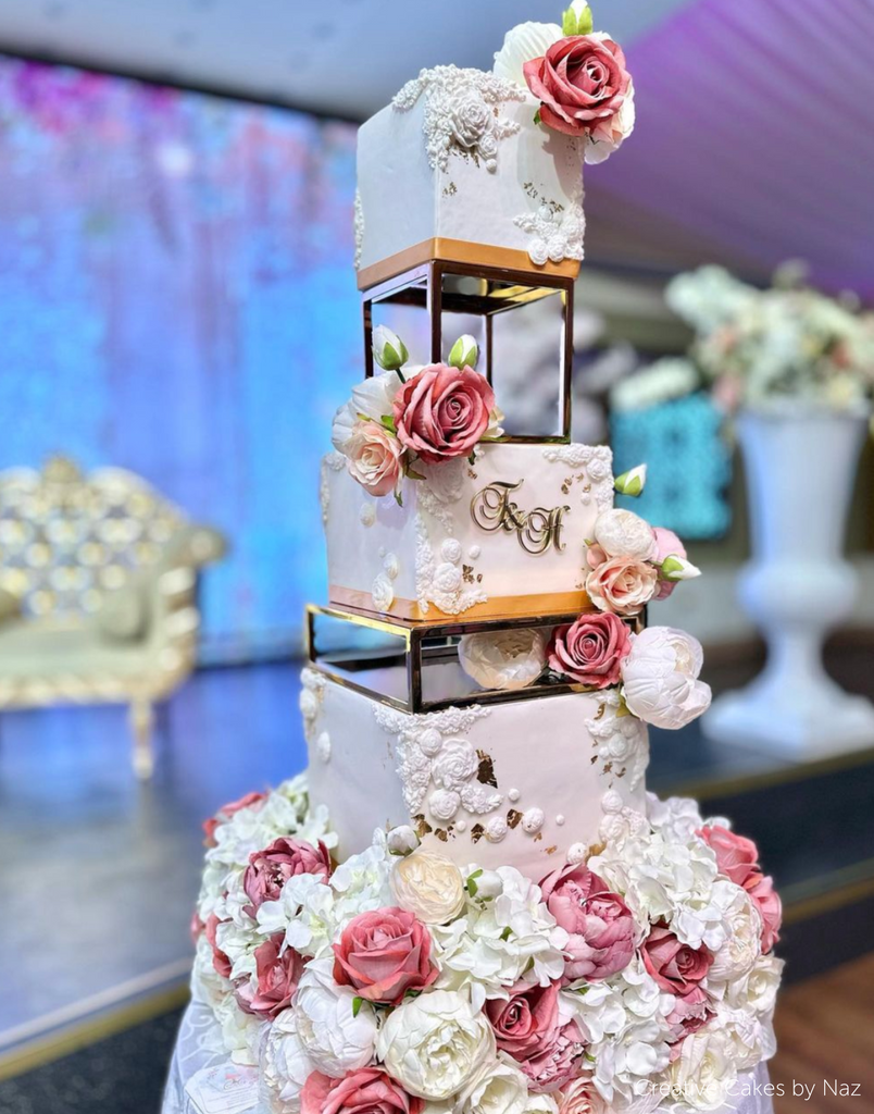 A white cake covered in pink and white flowers separated by Square and Rectangle Metallic Cake Spacers - Prop Options