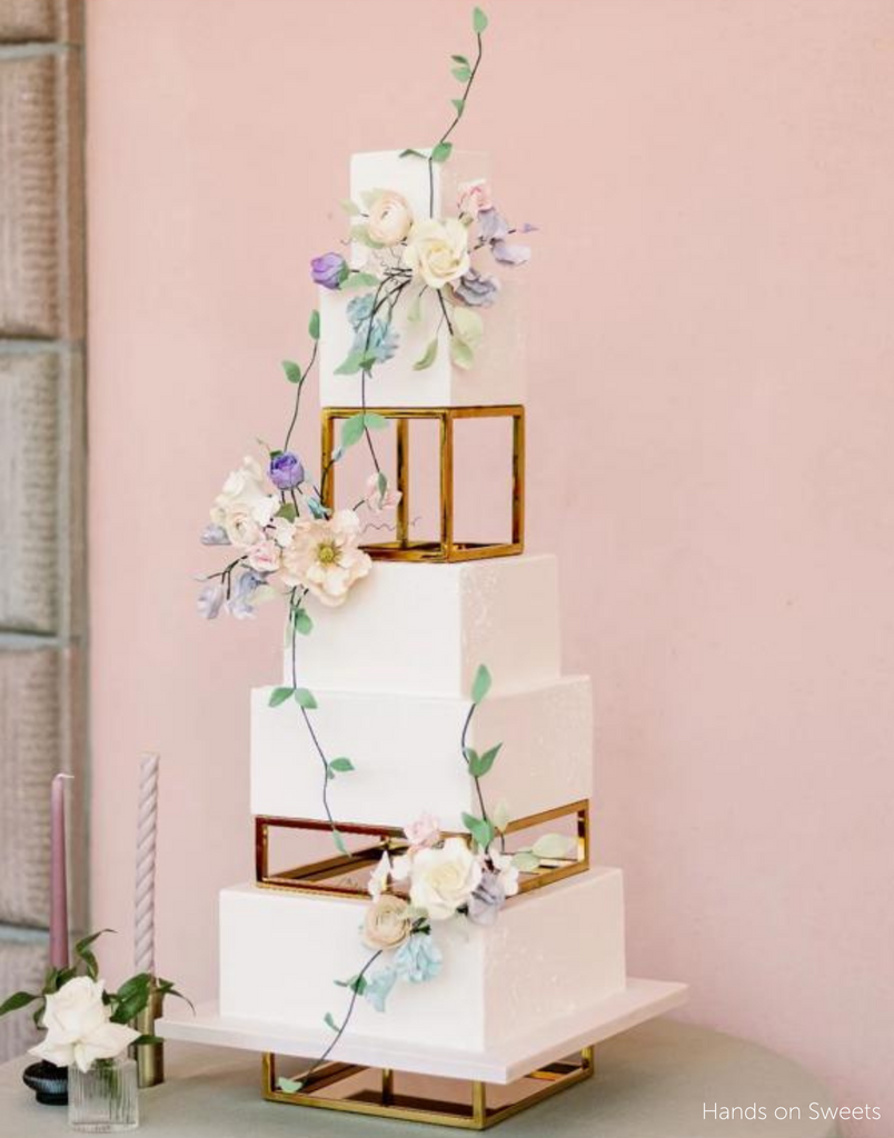 A white cake with pastel coloured flowers separated using Square and Rectangle Metallic Cake Spacers - Prop Options
