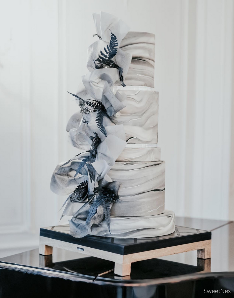 Elegant marbled white and grey cake with grey blue ribbon and leaf decorations down the side, the tiers are separated using 15mm Acrylic Cake Separators - Prop Options