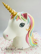 Unicorn cake with colorful mane and gold horn on a light background