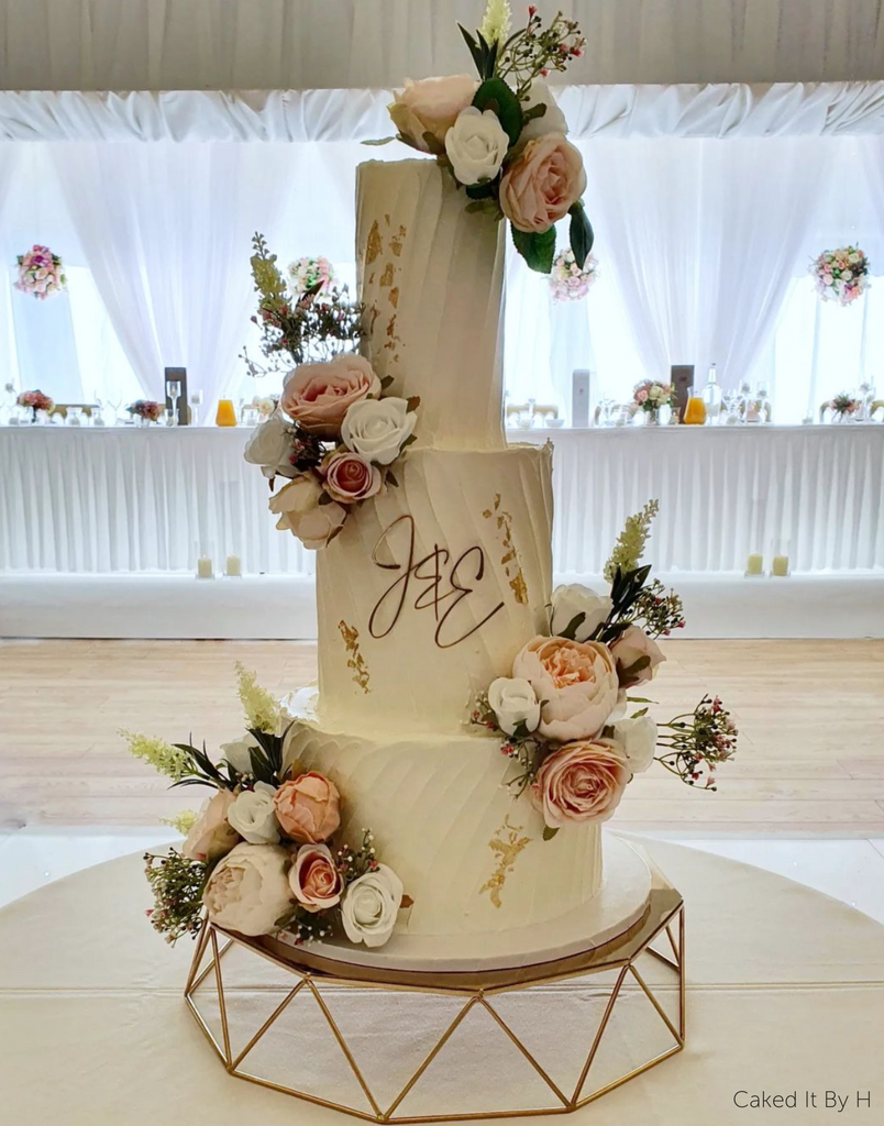 Geometric Cake Stand holding a white three layer cake covered in roses with the intitials J & E on the front - Prop Options