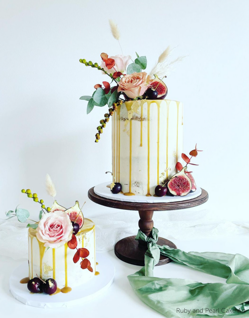 A white cake covered in flowers and fruit stood on The Original Scandinavian Birch Cake Stand - Prop Options