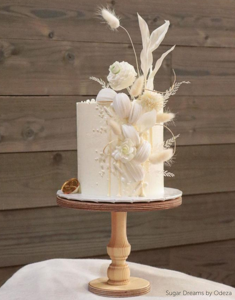 A white cake with light coloured florals stood on The Original Scandinavian Birch Cake Stand - Prop Options
