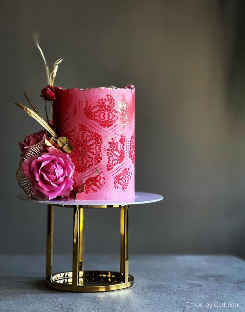Pink cake with dark pink decorations and flowers stood on a 6" Round Metallic Cake Spacer - Prop Options