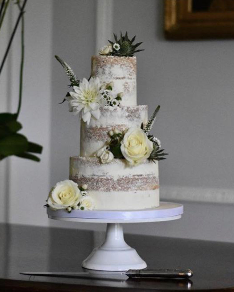Prop Options Carbon steel adjustable cake stand in white, shortened and displaying beautiful 3 tier nude wedding cake