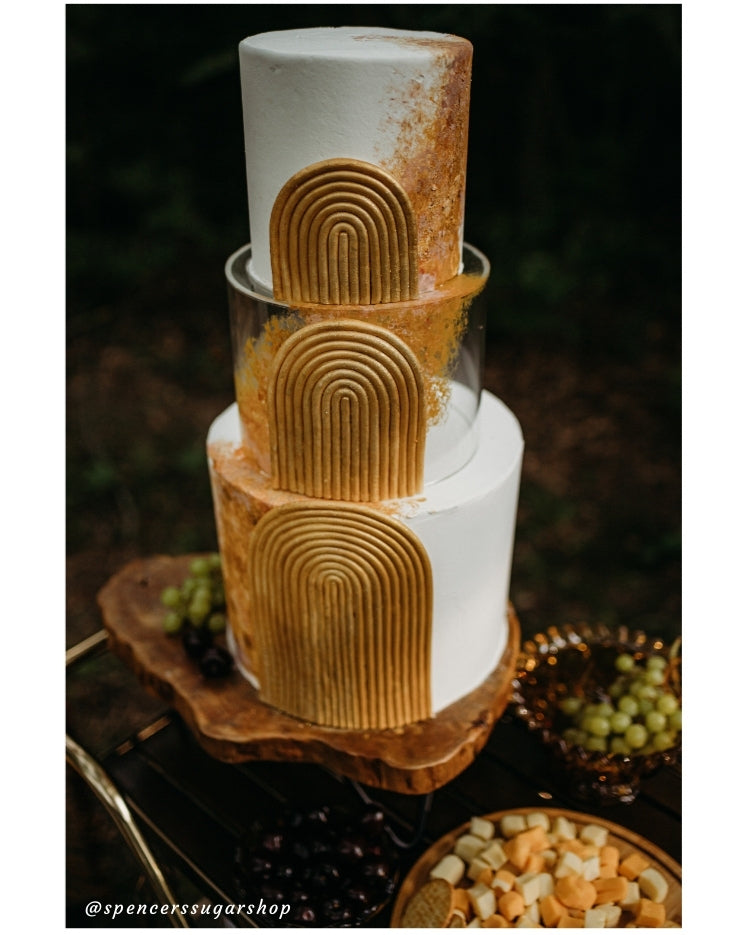 Design by Spencers Sugar Shop - exquisite detailing on gold and white cake in a forest picnic scene using Prop Options' clear tier and log slice stand - close up
